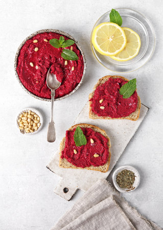 beetroot hummus in a bowl garnished with pine nuts and mint leaves. Served with lemon top viewの写真素材