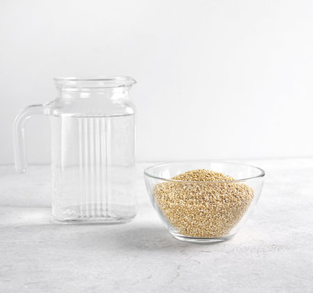 Quinoa seed in glass bowl and water in jug near to wash away the bitterness , food for healthy eating. copy spaceの写真素材