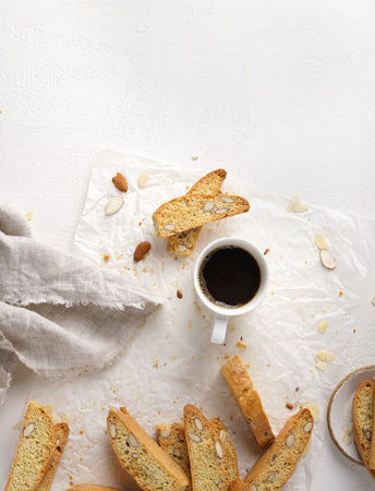Italian cookies (biscotti) with almonds and cup of coffee on the white table, top vie, copy space. Selective focus.の写真素材