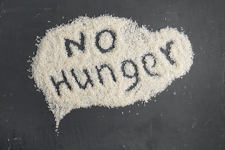 No Hunger text written on a rice scattered on a dark table. Food crisis, global hunger, food supply issue concept.の写真素材
