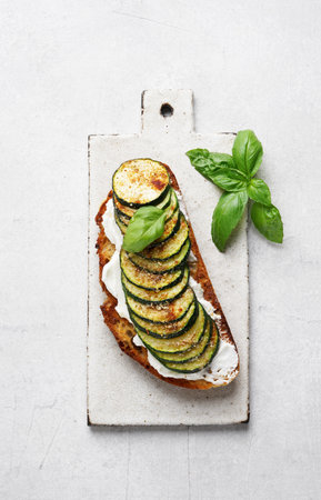 Delicious bruschetta with ricotta, grilled zucchini and herbs on a plate, top vertical view copy spaceの写真素材