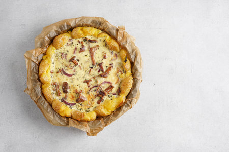 Top view of potato tart pie with chanterelles mushrooms, onion and cheese on white background, copy spaceの写真素材