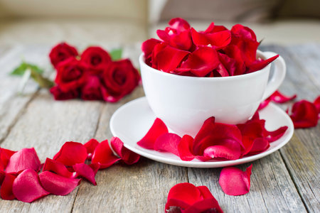 red roses and petal in white bowl on wooden backgroundの写真素材