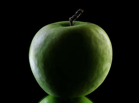 Green apple in dark isolated on black backgroundの写真素材