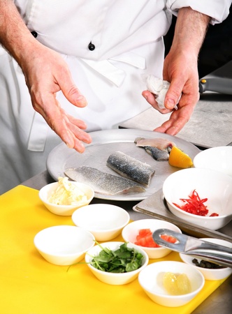 Chef preparing fish on professional kitchen in restaurantの写真素材