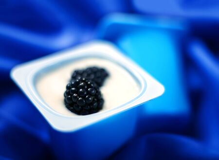 Yogurt with fresh blackberry on blue backgroundの写真素材