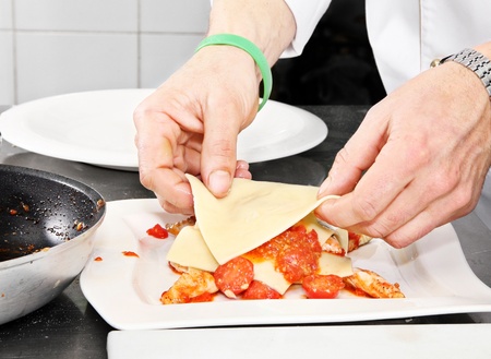 Chef preparing  lasagnawith red tomato and fishの写真素材