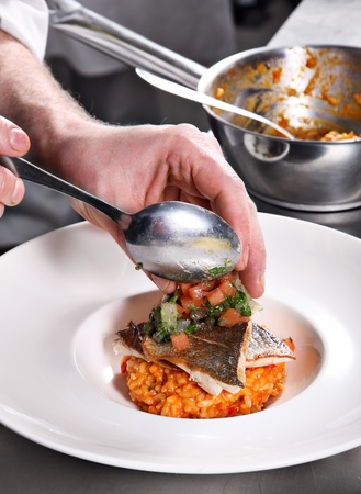Chef decorate fish risotto on professional kitchenの写真素材