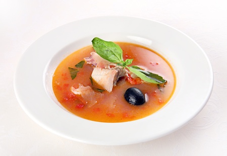 Preparing food fish soup with vegetable on white plate