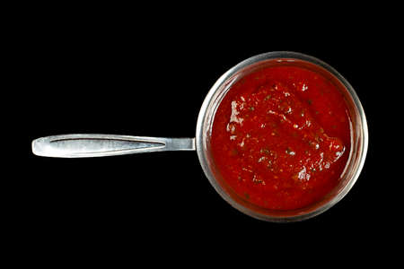 Tomato sauce in metal saucer isolated on black backgroundの写真素材