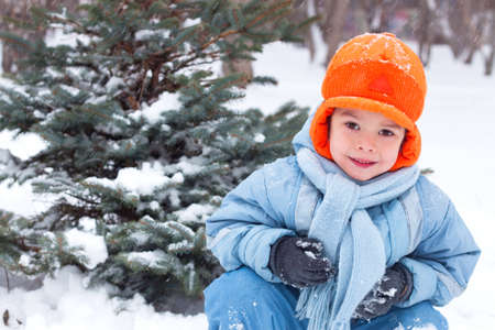 little boy playing snowballs, snowman sculpts, digs snow,の写真素材