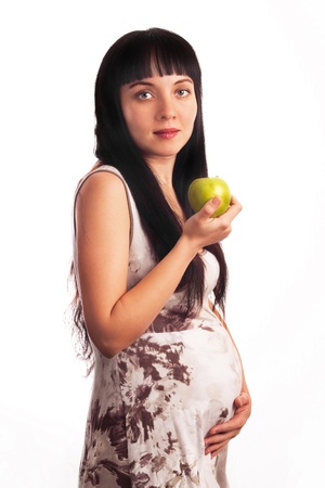 Beautiful, young pregnant girl is eating an Apple. Mom, Mother, Motherhood, waiting for the child birth.の写真素材