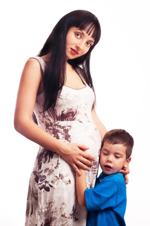 A beautiful little boy pressed against her stomach pregnant youn, a pregnant mother and son. Motherhood.の写真素材