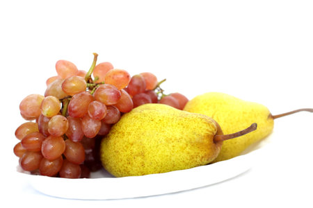 Grapes and pears on a white plateの写真素材