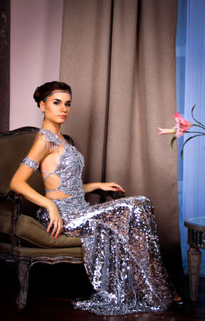 young beautiful girl in a shiny dress in the roomの写真素材