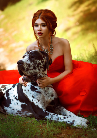 young beautiful girl in a red dress with a big dogの写真素材
