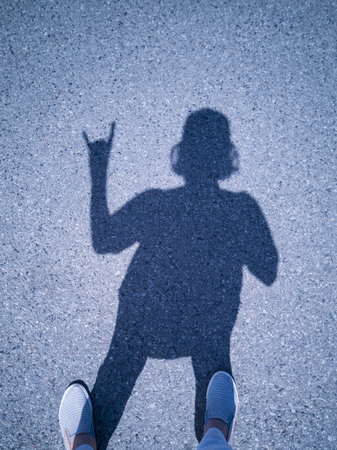 shadow of a girl on the asphalt. shadow from the bright sun.の写真素材