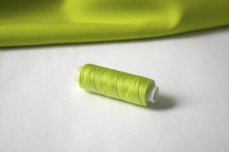 tools for sewing and needlework. green threads and green fabric.