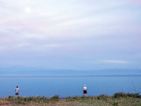 Fisherman fishes early in the morning on the shore. Fishing rod and spinning. Campingの写真素材