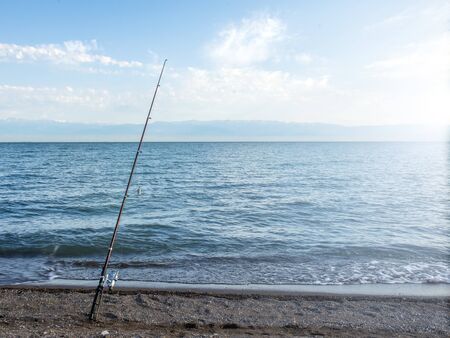 Fisherman fishes early in the morning on the shore. Fishing rod and spinning. Campingの写真素材
