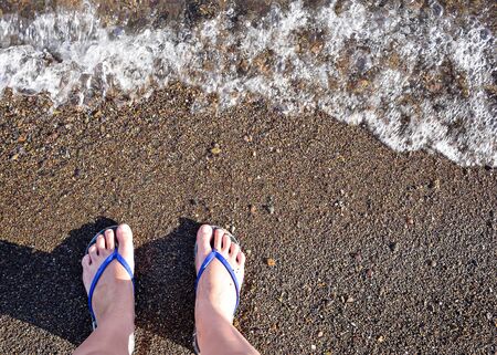 A man walks barefoot on the beach. Human legs in the water. Waves beat on the legs of man. Relax.の写真素材
