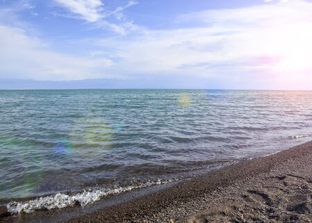 Wild beach lake. The coastline of the sea. Brown sand and blue sky. Mountain View. Rest on the coast.の写真素材