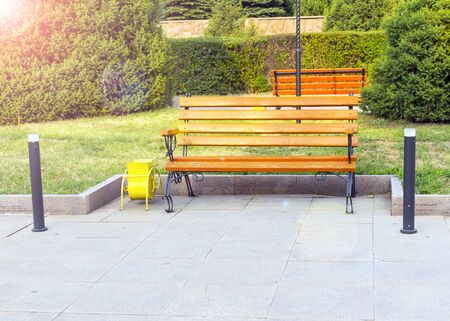 Lantern and park bench. Camping. A beautiful place in the city. A bench stands near green trees. Lantern for street lighting. A place to relax.の写真素材