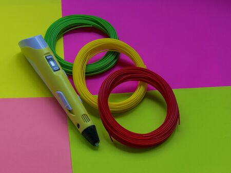 3D pen and spare parts made of plastic lie on a colorful background. Plastic for 3D pens. Modern...