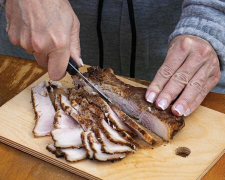 Girl cuts ham on a picnic. Sliced pork meat. Slicing and snack on a vacation in nature. Pork steak.の写真素材