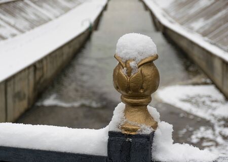 The first snow lies on the railing of metal near the river in the city. Frozen railing. Cold winterの写真素材