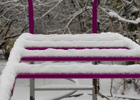 The playground is covered in snow. Children's slide and stairs. Happy childhood. Winter and snowfall.の写真素材