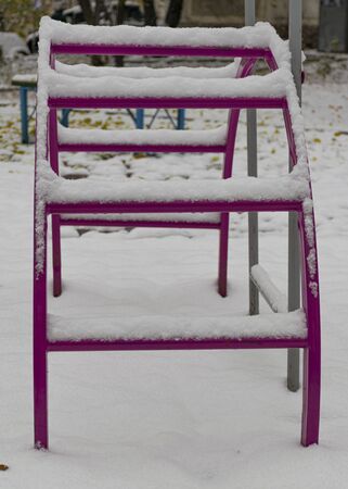 The playground is covered in snow. Children's slide and stairs. Happy childhood. Winter and snowfall.の写真素材