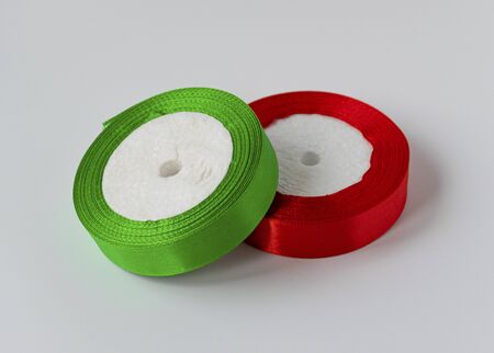Roll of satin ribbon for decorating gifts on a white background. Silk and satin ribbon of red and green color.の写真素材