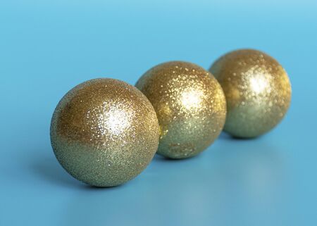 Golden shiny ball to decorate the Christmas tree for the New Year and Christmas on a blue background.の写真素材