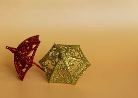 Golden shiny toys in the form of an umbrella to decorate the Christmas tree for the New Year and Christmas on an orange background. Decor for the holiday.の写真素材