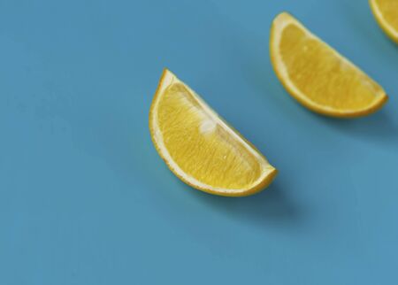 Bright juicy slices of lemon on a blue background. Yellow lemon. Citrus and vitamins.の写真素材