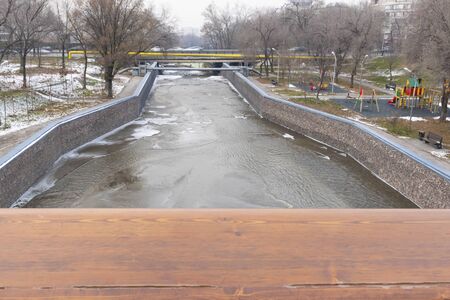 A brown wooden board with a blurry winter background of a frozen river and a view of the playground. Cold weather. Wood surface for design.の写真素材