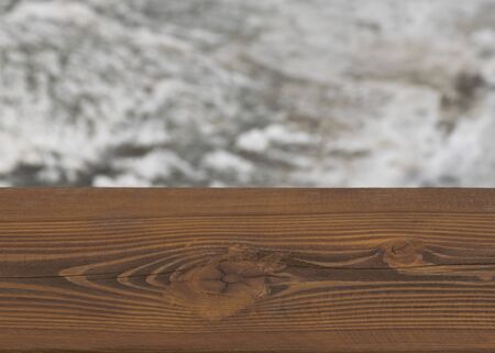 Brown wooden board with blurry winter background of a frozen river. Cold weather. Wood surface for design.
の写真素材