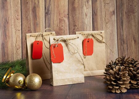 Vintage handmade gift boxes made of kraft paper on a wooden background in the Christmas style, decorated with golden Christmas balls, cones, fir branch. Christmas, New Year, winter holiday. Kraft package, holiday concept, top view, flat lay. Mocap.の写真素材