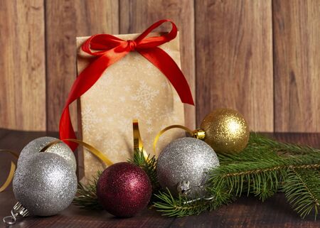 Gift bag made of handmade kraft paper on a wooden background in a Christmas style, decorated with Christmas tree balls, cones, a ball of rope, fir branches. Christmas, New Year, winter holiday. Kraft package, holiday concept, top view, flat lay.Mocap.の写真素材
