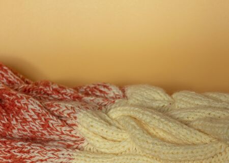 Beige and orange knitted clothes on an orange background. Beautiful knitting. Gradient. Copy space flat lay top view.の写真素材