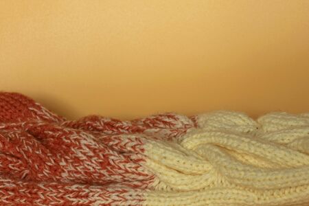 Beige and orange knitted clothes on an orange background. Beautiful knitting. Gradient. Copy space flat lay top view.の写真素材