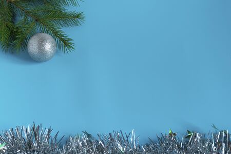 Silver shiny Christmas decorations, spruce branch, balls for the Christmas tree, bows, tinsel on a blue background, top view.
の写真素材