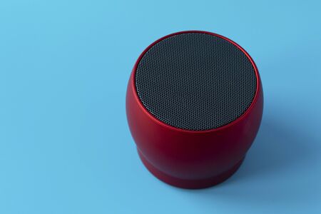 Wireless and powerful red speaker on a blue background. Speaker to enhance volume and sound.の写真素材