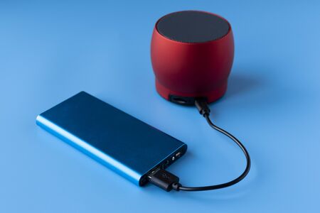 Power bank for charging mobile devices and devices. Blue smartphone charger with power bank. External battery for wireless headphones and speakers on a blue background.の写真素材