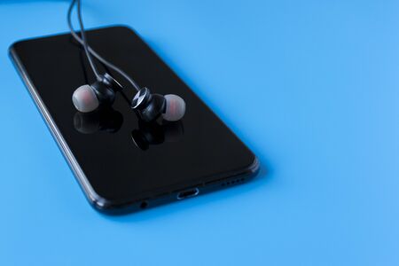 Black wireless headphones for the phone on a blue background. Headset for the phone.の写真素材