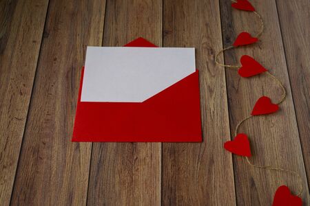Background for Valentine's Day. Garland of hearts, red envelope on a wooden background. Valentine .の写真素材