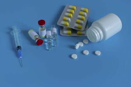 A bottle of medicine next to a syringe. Medicines for the virus and flu. Medical pills and antibiotics. Coronavirus, personal protective equipment, medicine with a syringe, vaccine and tablets. Virus, healthcare and medicine concept.の写真素材