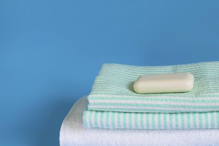 Soft and fluffy towels on a blue background. Soap for bath, laundry and body care. Personal hygiene products. Bath amenities, spaの写真素材