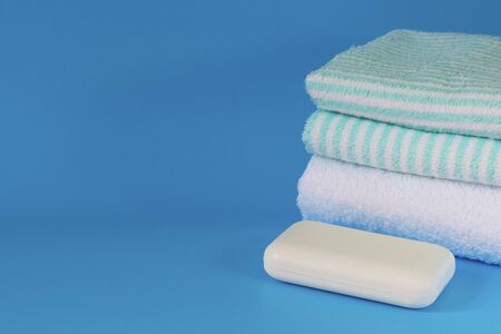 Soft and fluffy towels on a blue background. Soap for bath, laundry and body care. Personal hygiene...